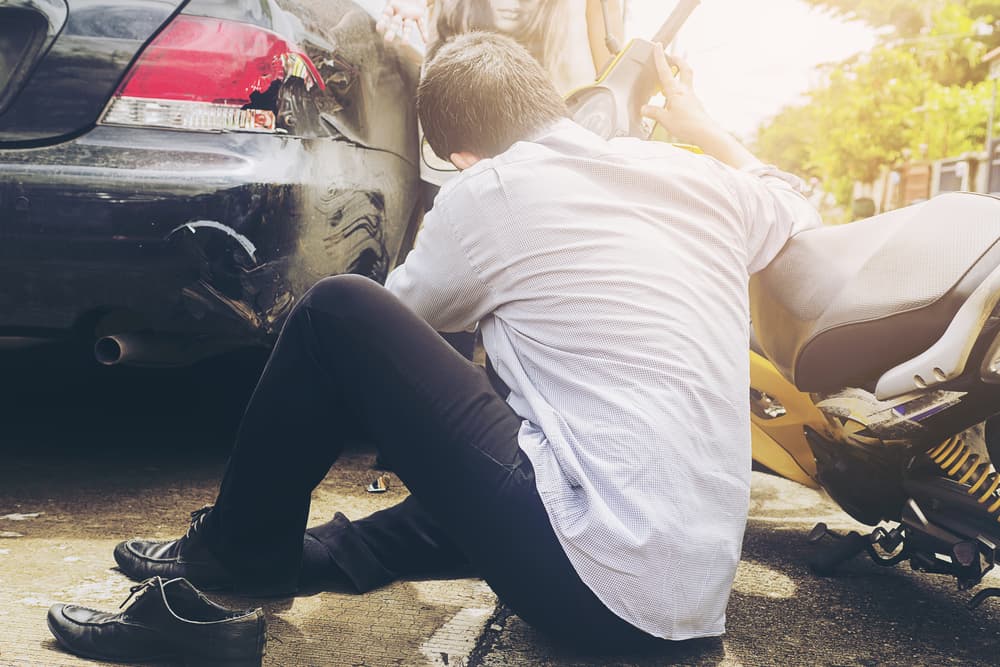 Collision between car and motorcycle, showing an injured rider on the motorcycle.