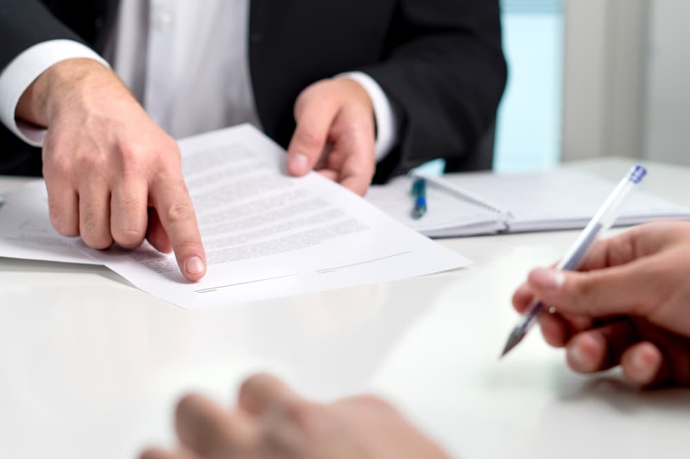 Signing a insurance settlement offer. Lawyer showing client the line for autograph in a document paper.