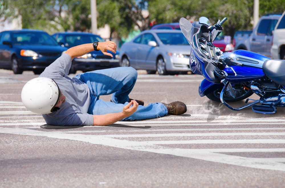 A biker has taken a tumble, with his blue motorcycle fallen beside him on a busy city street in San Antonio.