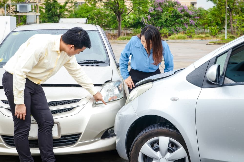 Exploring car insurance concept: People assess damaged cars after a road accident, preparing to file insurance claims.