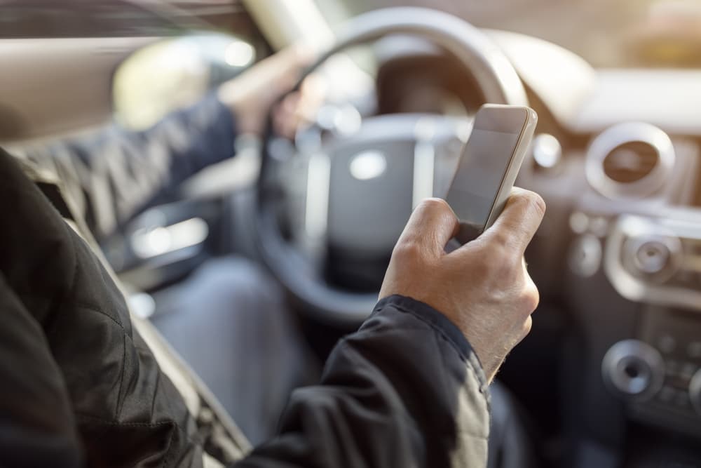 Illustration depicting the risks of distracted driving – a person using a phone in a car, emphasizing the dangers of texting while driving.